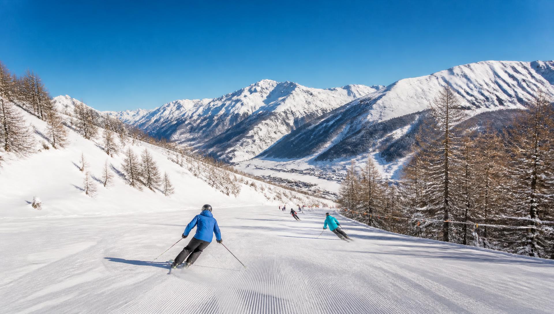 Snow-covered ski slope with piste grooming vehicle in Livigno, Italy