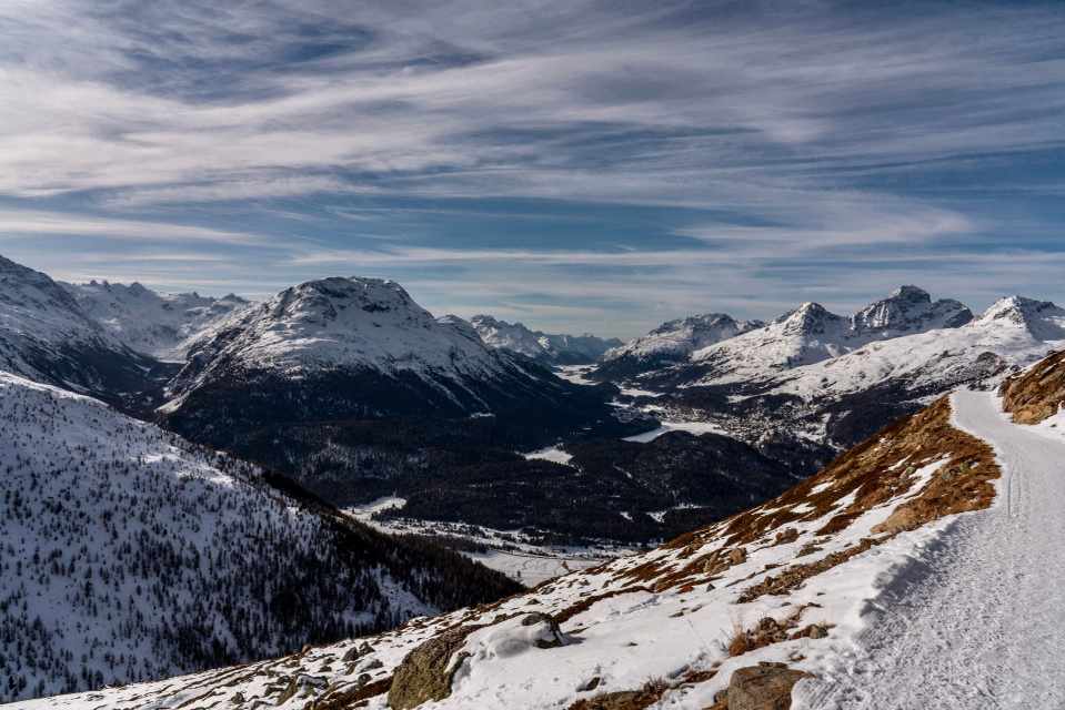 Snow-covered mountains and the Upper Engadin valley near St. Moritz beneath a streaked blue sky