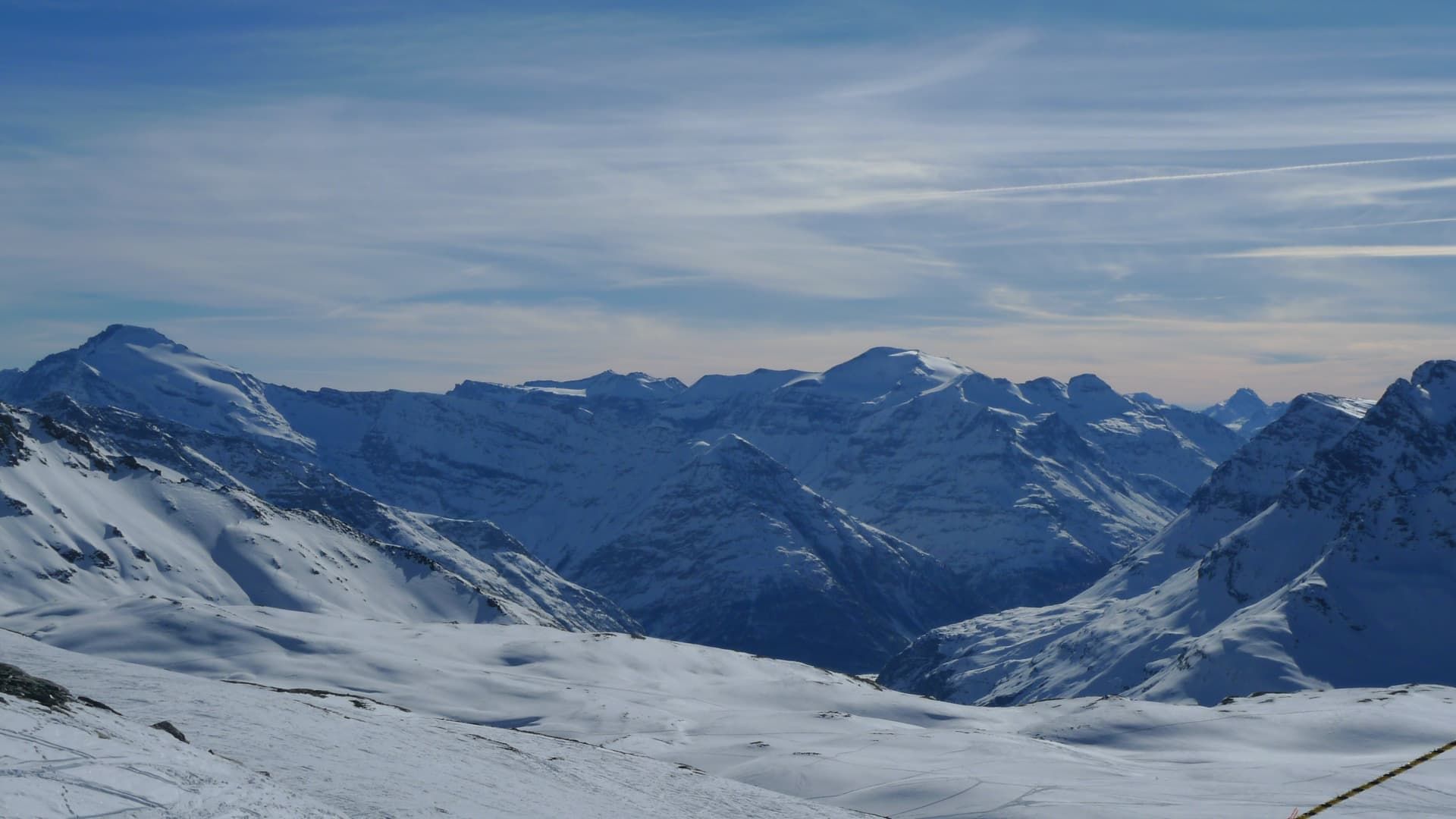 Snow-covered peaks and pistes in the Val d’Isère ski area under a blue winter sky