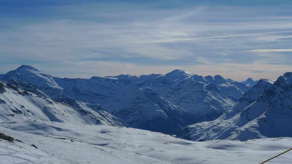 Snow-covered peaks and pistes in the Val d’Isère ski area under a blue winter sky